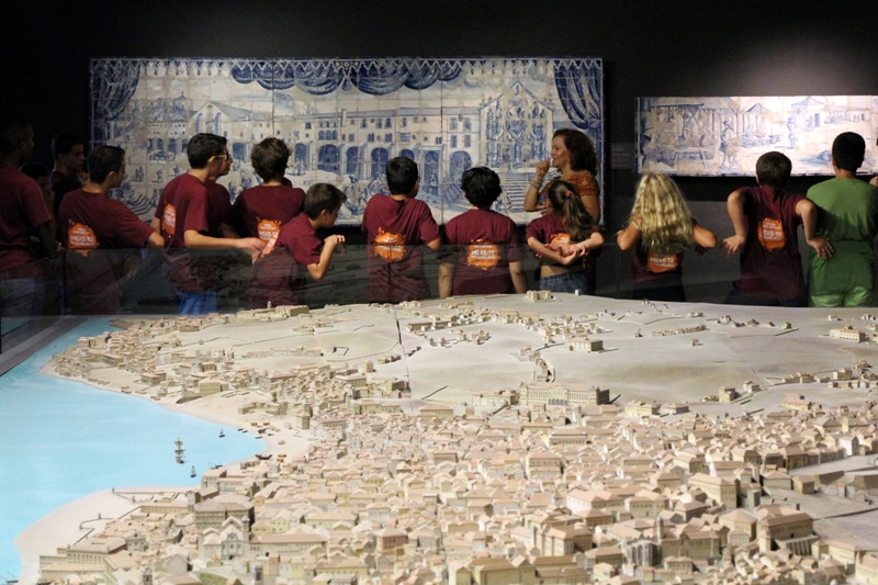 Grupo de crianças num museu a ver um painel de azulejos alusivo a Lisboa antiga