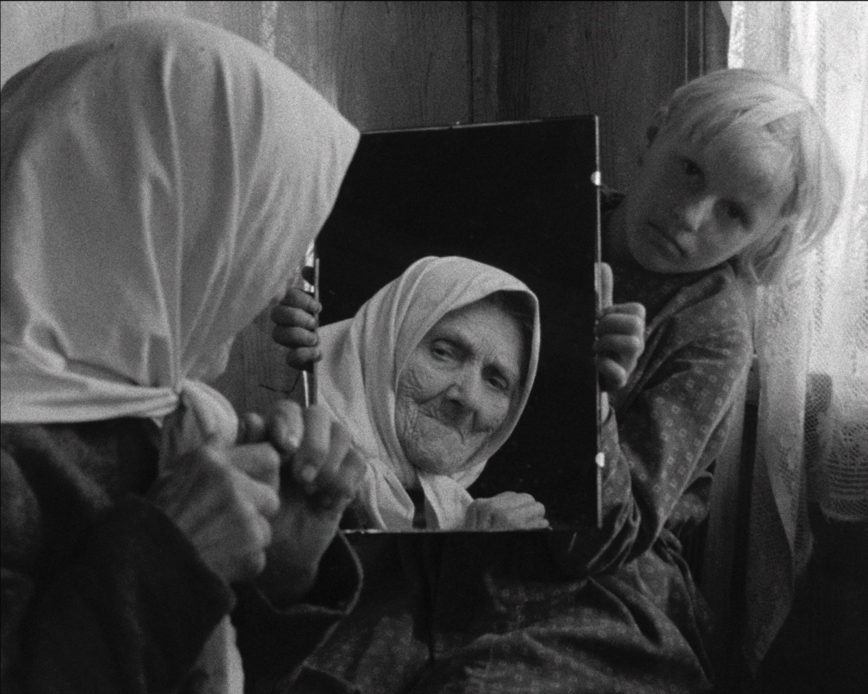 cena de um filme onde uma criança segura um espelho onde é refletida a imagem de uma senhora idosa