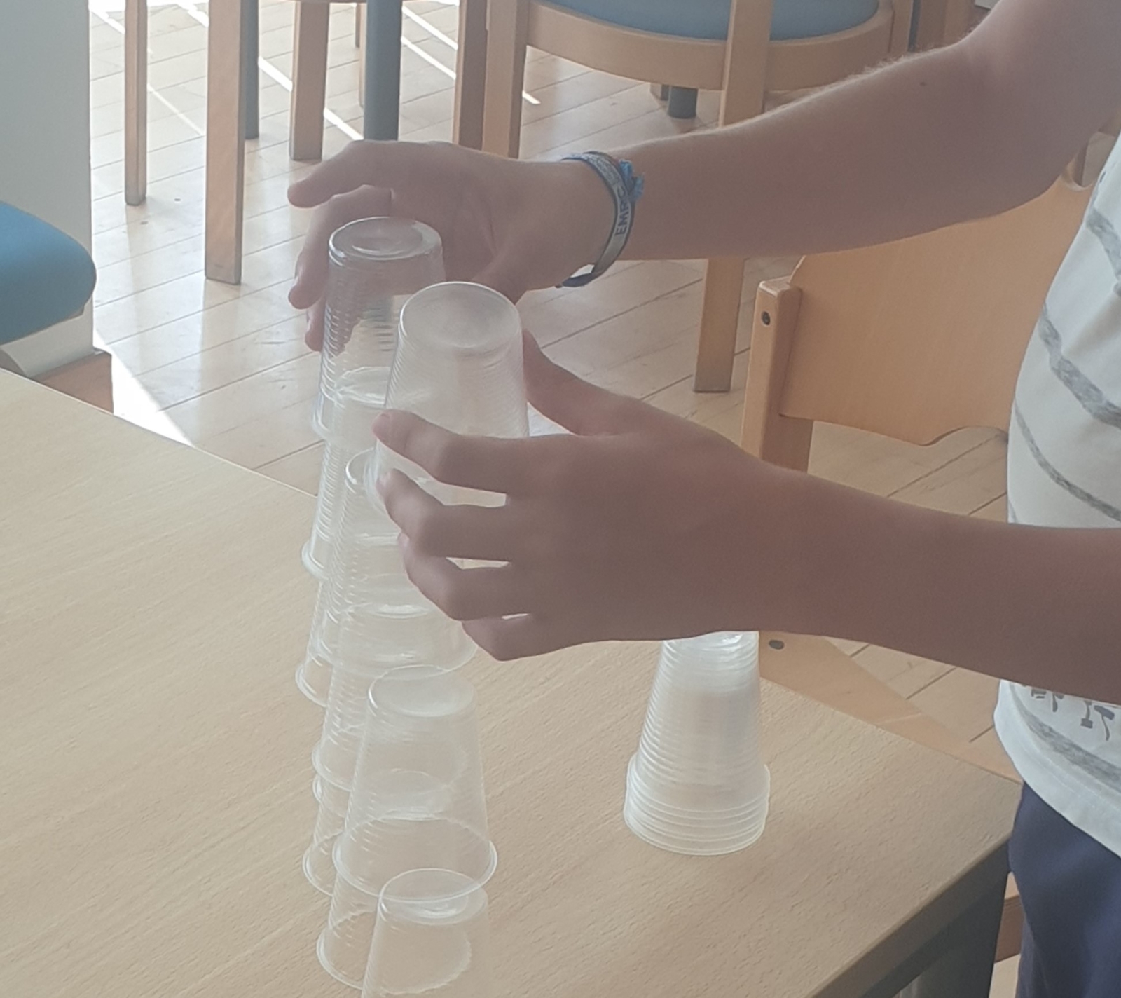 Criança a jogar um jogo com copos de plástico em cima de uma mesa